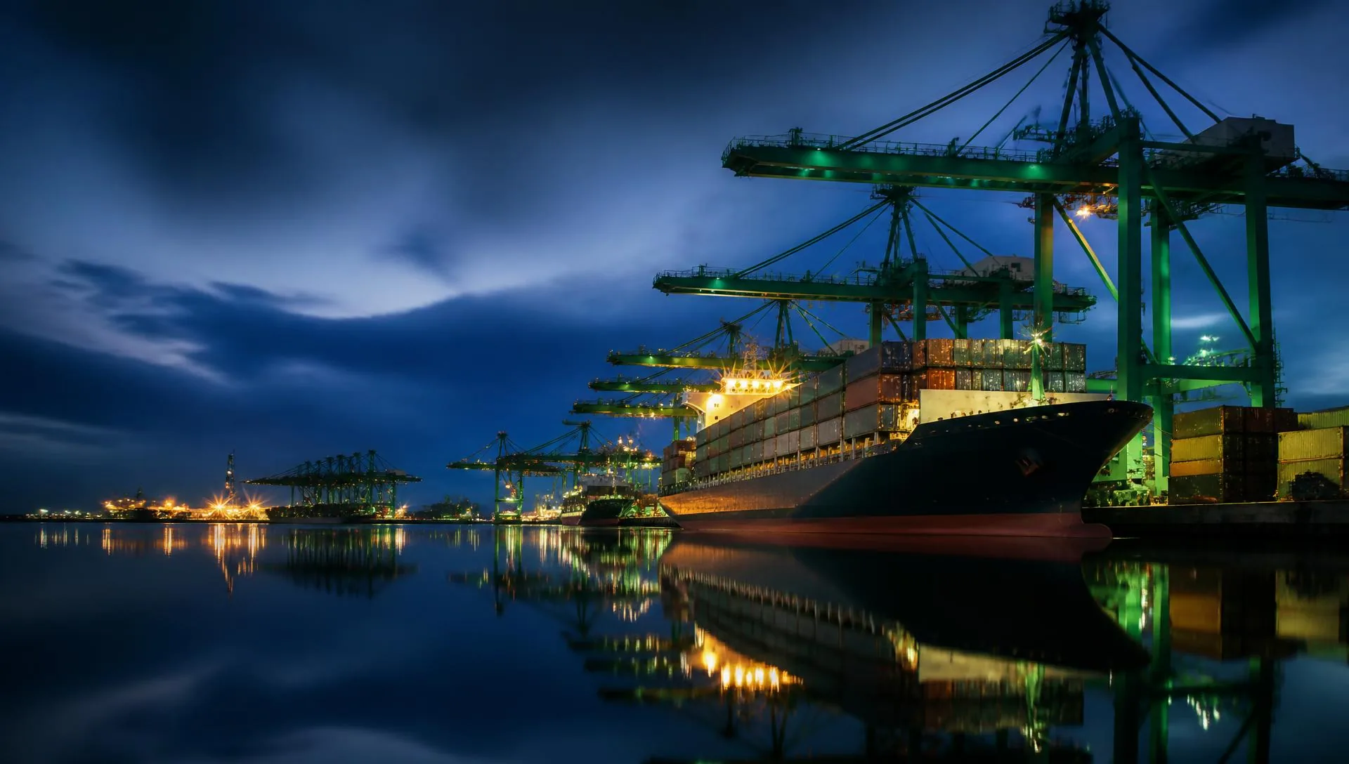 Container terminal at blue hour with cranes and a loaded vessel